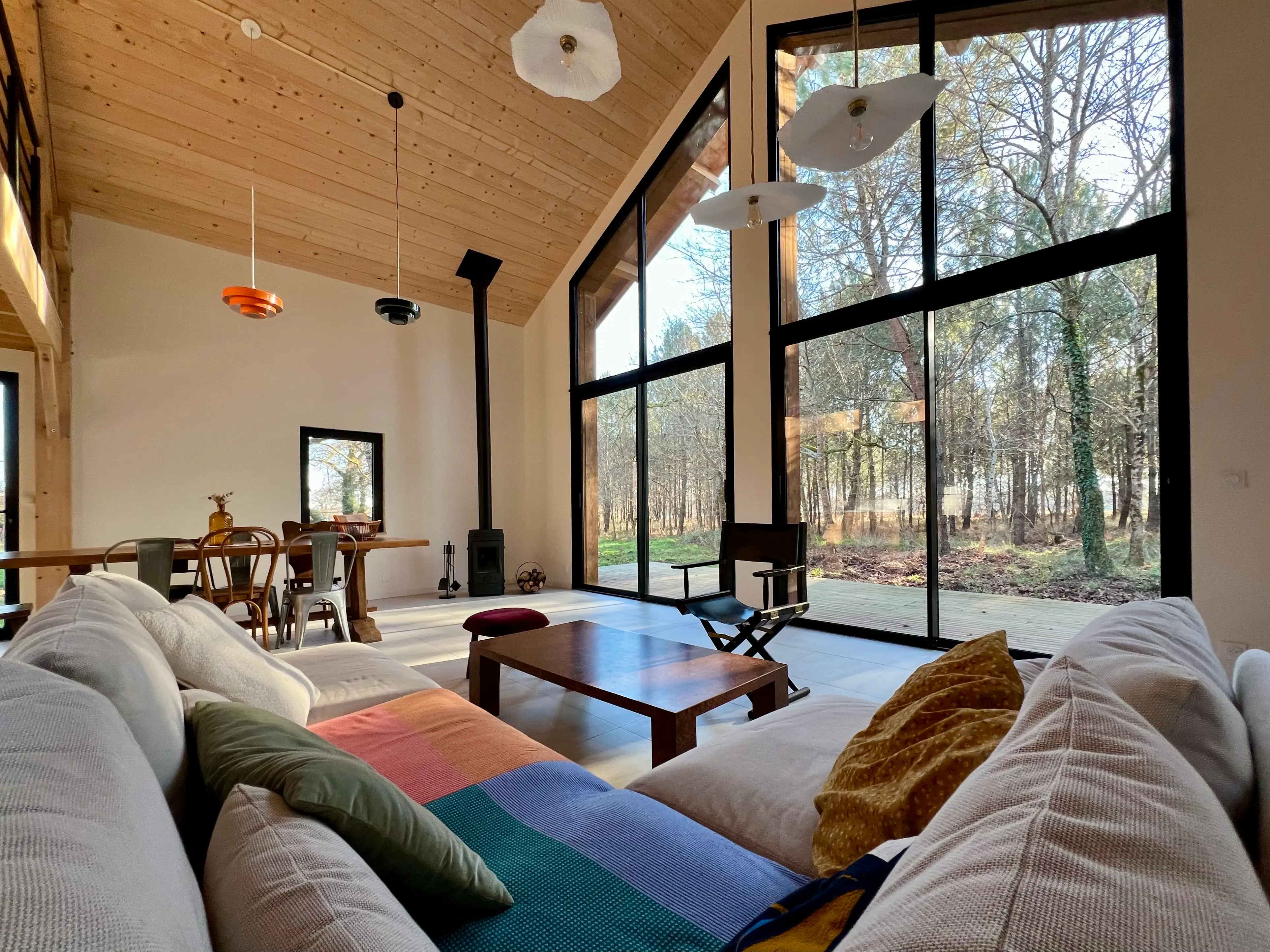 Salon lumineux avec grandes baies vitrées vue forêt - Location Landes